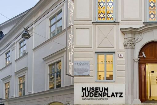 The photo shows a photomontage of the two locations of the Jewish Museum Vienna, on the left the façade of the Jewish Museum in Dorotheergasse, on the right the entrance to the museum on Judenplatz with the lettering Museum Judenplatz to the left of the e