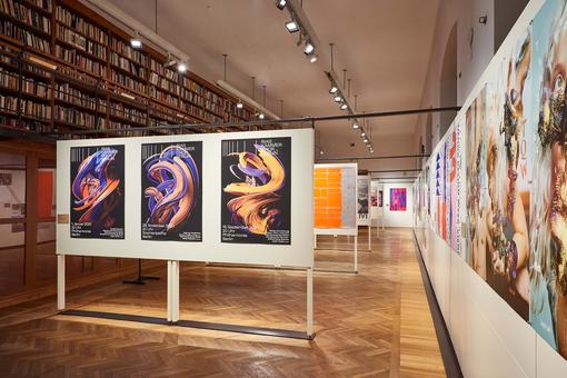Exhibition view with differently designed posters on white partitions