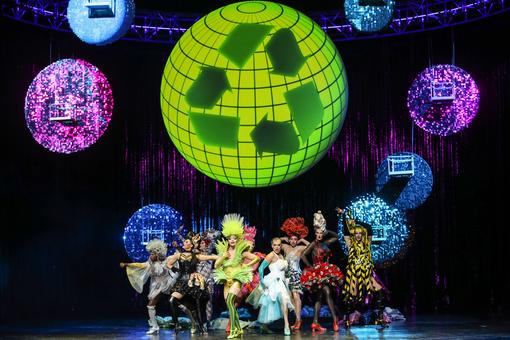 Scene photo from the musical "La Cage aux Folles" with numerous drag queens in outlandish costumes