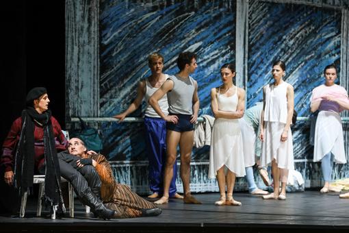 Szenefoto aus dem Familienstück "Nurejews Hund" der Volksoper Wien. Zu sehen sind die Darsteller des Nurejew und seines Hundes, rechts neben ihnen MIglieder einer Ballett-Kompanie