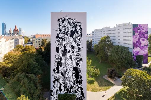 Das Foto zeigt zwei Murals vom Calle Libre Festival 2024 auf zwei Wohnhäusern in Wien, eines ist in den Farben Schwarz und Weiß und zeigt unzähliche unterschiedlich Figuren, das zweite Mural in den Lilatönen mit Blütengesichtern