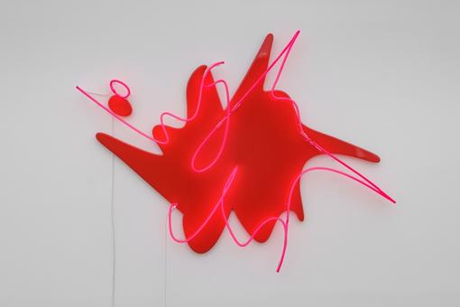 The photo shows a neon red light installation called “A candle to earth” mounted on a white wall