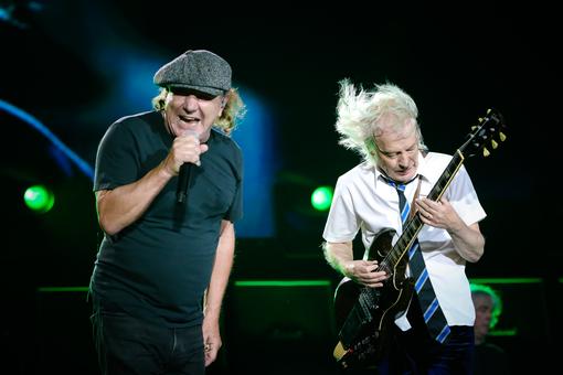 Photo of two of the band members: singer Brian Johnson with mic in hand, Angus Young on lead guitar