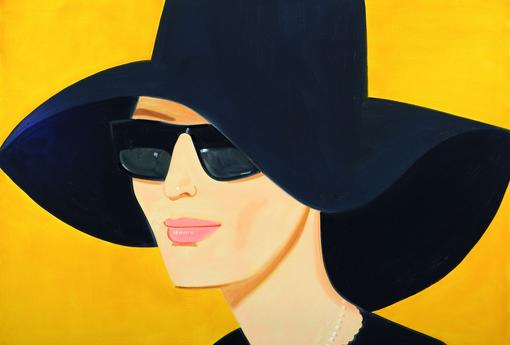 Porträt einer Frau mit schwarzen breitkrempigen Hut und schwarzer Sonnenbrille vor gelbem Hintergrund