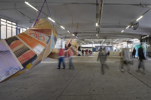 Exhibition view with in a colorful installation that snakes through a hall like a chain of boxes