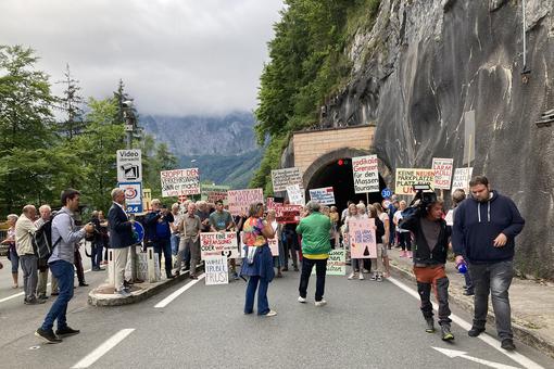 Foto demonstrierender Bewohner:innen von Hallstatt mit Plakaten vor dem Tunnel, der nach Hallstatt führt