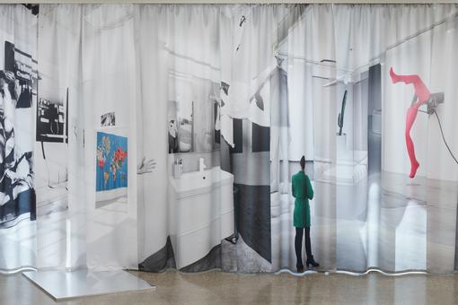 Das Foto zeigt eine Ausstellungsansicht der Schau "Limited Company" des britischen Künstlers Jonathan Monk. Zu sehen ist ein mit Fotomotiven bedruckter, leicht durchscheinender Vorhang 