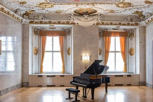 Photo of a concert grand piano in a baroque concert hall