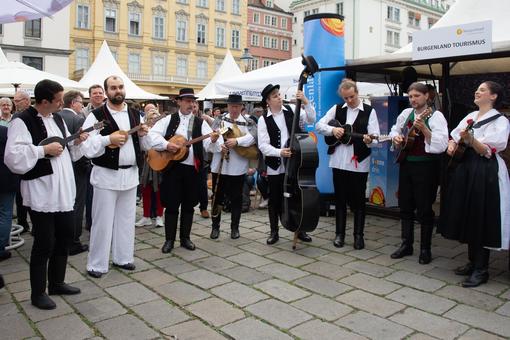 Foto einer burgenländischen Musikgruppe in authenitscher Tracht, die zwischen den Ständen aufspieltFoto einer burgenländischen Musikgruppe in authenitscher Tracht, die zwischen den Ständen aufspielt