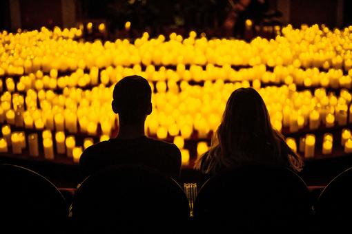 Rear view of two people in front of a sea of burning candles