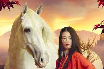 The photo shows a section of the event poster with the head of a white horse and an Asian woman with long black hair