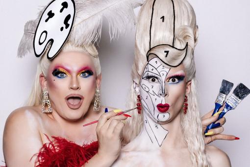Photo of the two drag queens © Kleinkunstprinzession & Metamorkid with white wigs, one paints the face of the other one