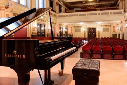 Photo of the renovated Ehrbar Hall, with a view from the stage into the hall, in the foreground a concert grand piano from the C. Bechstein company.