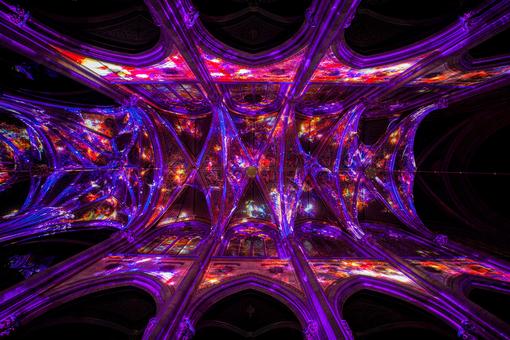 The photo shows the Gothic vault of the Votive Church filled with light effects in the colors pink, purple, blue, orange