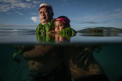 Das World Press Photo zeigt zwei Inselbewohner:innen im Südpazifik, einen Mann und eine Frau, die aufgrund des steigenden Meeresspiegels bis zum Hals im Wasser stehen