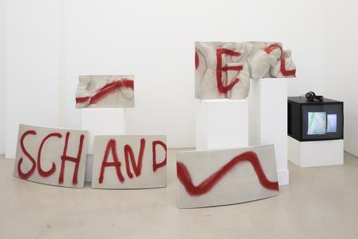 Exhibition view: individual wall blessings in white with red lettering "Shame" on the individual segments.