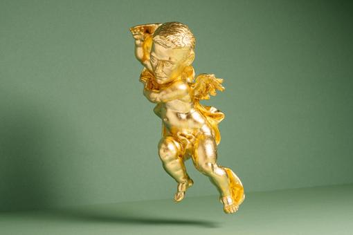 The photo shows a small golden statue of a man depicted like a baroque putto