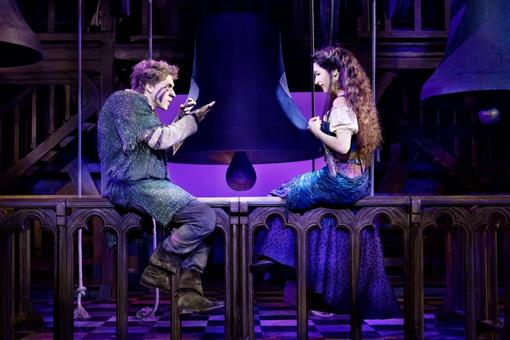 Scene image from the musical "The Hunchback of Notre Dame": Quasimodo and Esmeralda sitting on a railing of the cathedral