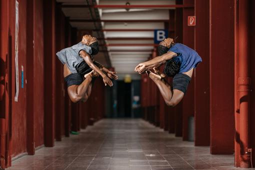Two dancers photographed doing a dance figure synchronously but mirror inverted in the air