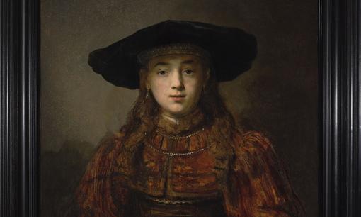 The photo shows a detail of the oil painting Girl in a Picture Frame by Rembrandt. The girl is wearing a precious brown velvet robe, long brown hair and a black hat
