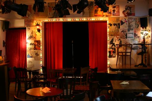 Photo of a cabaret stage in front of it some tables and chairs
