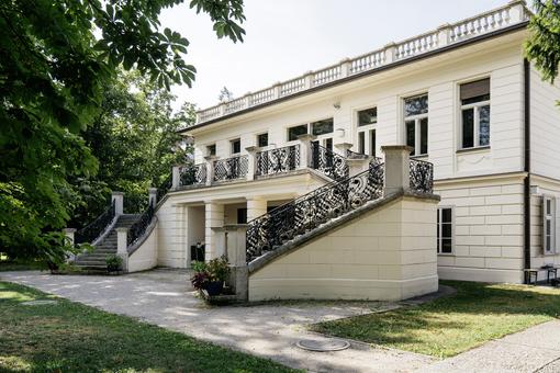 Foto der Klimt Villa mit Stiegenaufgang in den ersten Stock, umgeben von einem Garten