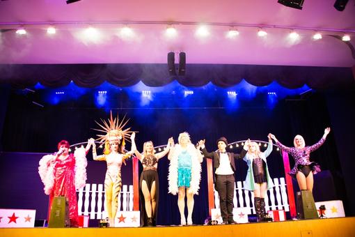 Sieben Künstler:innen in unterschiedlichen Kostümen, die den Applaus auf der Bühne entgegennehmen