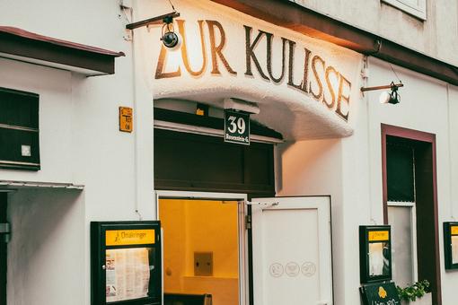 Exterior view of the cabaret Kulisse with the entrance door, above it the lettering Kulisse, which is illuminated with spotlights