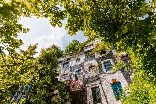Ansicht der Außenfassade des Kunst Hauses Wien eingerahmt vom üppigen Grün der umliegenden Bäume