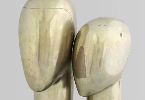 A sculpture with two abstract golden heads facing each other