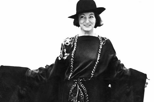 Black and white photograph of Gertie Fröhlich in dark dress, cape and hat