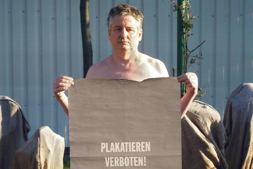 Foto das einen Mann zeigt, der ein Stück Packpapier vor sich hält, mit der Aufschrift: Plaktieren verboten!