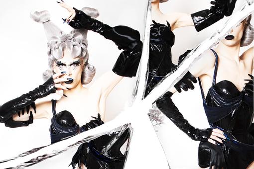 Photo of drag queen with flashy wig with white and silver hair, in black vinyl corsage and black long vinyl gloves