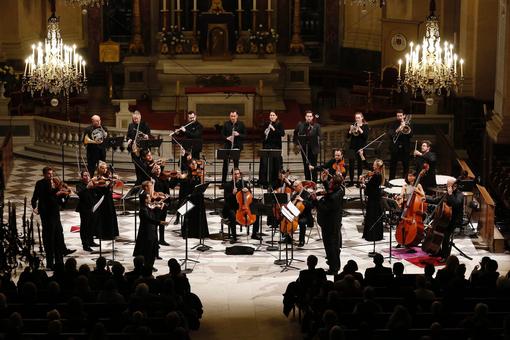 Foto einer Konzertszene mit dem Morphing Chamber Orchestra stehend vor dem Altar einer Kirche
