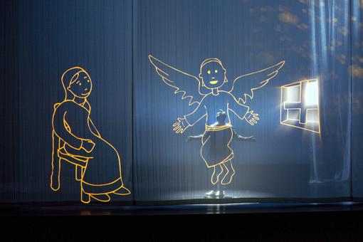 Theaterbühne mit Lichtprojektion eines Engel und Mädchens im Sessel