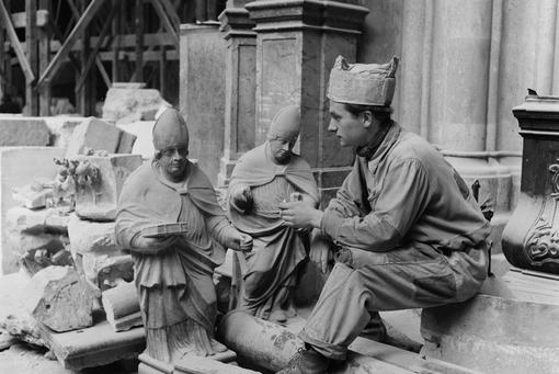 Black and white photo of a stonemason with sacred statues in front of St. Stephen's Cathedral in Vienna