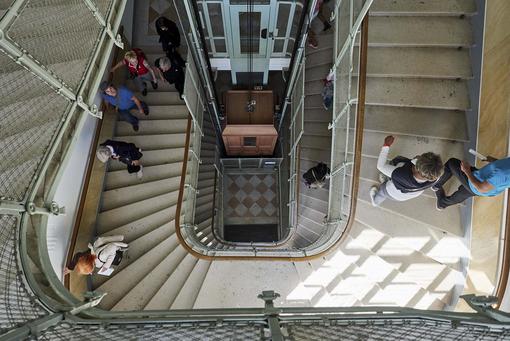Photo of a Mid-Century staircase from above, through which visitors:inside go up the stairs