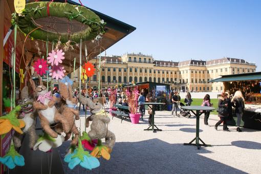 The photo shows the Easter market with its colorfully decorated stalls in front of Schönbrunn Palace
