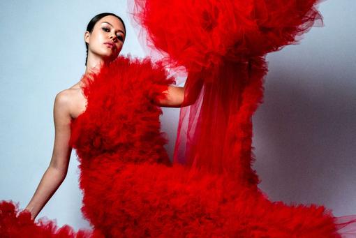 Foto eines Models in einem Outfit von Nicolas Dudek: ein rotes, langes, sehr aufgebauschtes Tüllkleid mit langer Tüllstola oder -schleppe
