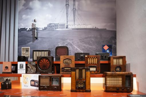 Zu sehen ist eine Ausstellungsansicht mit vielen unterschiedlichen historischen Radiogeräten