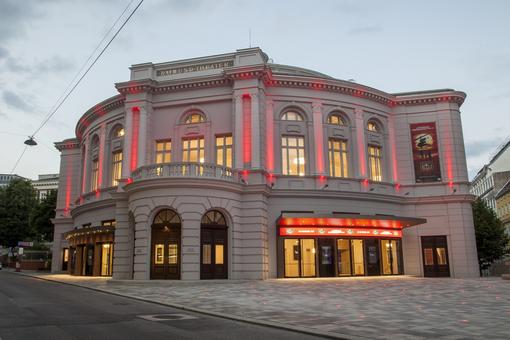 Exterior view of Raimund Theater in the early evening with evening lighting in red tones
