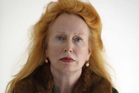 Portrait photo of Rebecca Horn with open red hair in green manel with fur trim