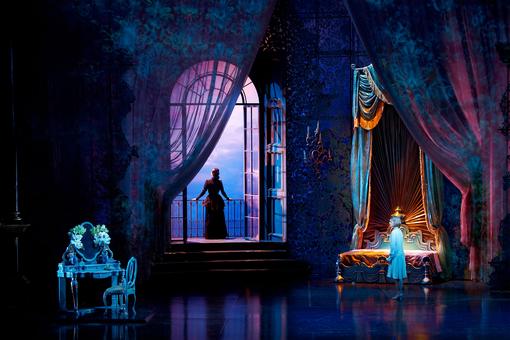 Scene image from the musical, the bedroom in shades of blue and purple, Rebecca stands on the balcony and looks into the distance