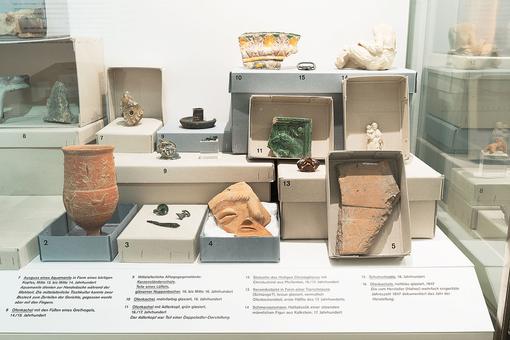 Foto mit unterschiedlichen archeologischen Fundgegenständen wie Tonvasen, Scherben, Figuren