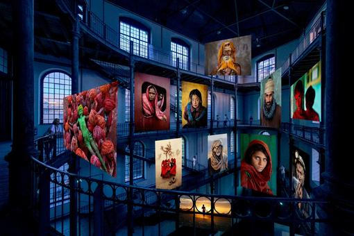 Ausstellungsansicht: Großformatige, farbintensive Fotografien, die auf verschiedenen Ebenen durch den weiten Innenraum des Wiener Semperdepots schweben