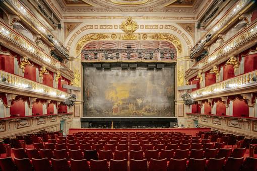 Innenansicht des Theaters an der Wien, im Hintergrund die Bühne mit dem eisenen Vorhang, seitlich die kunstvoll gestalteten Logen und im Vordergrund die Bestuhlung des Parketts