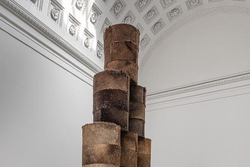 The photo shows an installation of brown rolls made of camel hair and leather in the room of the Temple of Theseus