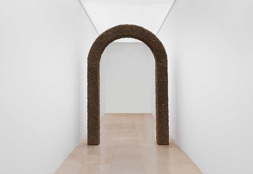 The photo shows an archway covered with earth against a white background