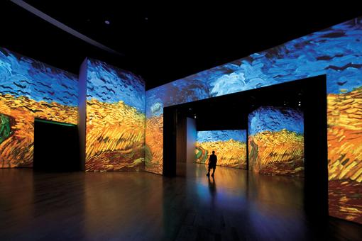 Photo of a multimedia exhibition: paintings by Van Gogh in shades of blue and yellow projected onto walls