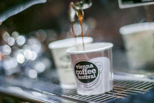 Foto von einem Kaffeebecher mit dem Logo des Vienna Coffee Festivals in den frisch gebrühter Kaffee läuft